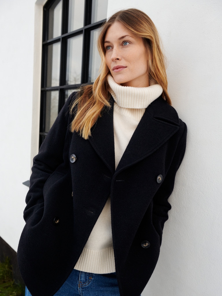 Woman in white knit and black wool coat